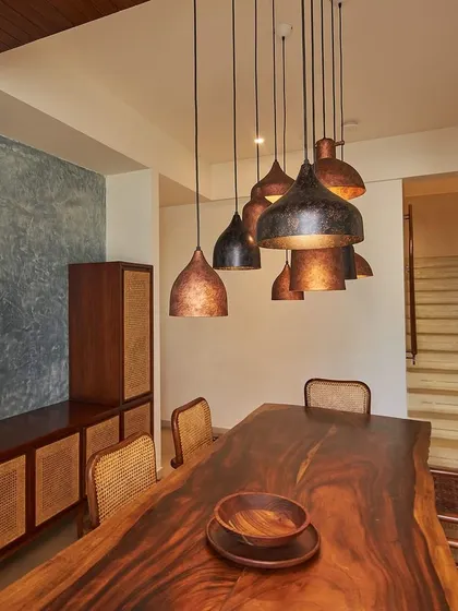This dining space from the Magnolia Residence uses a live-edge wood table paired with cane chairs and custom pendant lights. The design creates a warm, inviting atmosphere that is both elegant and comfortable.