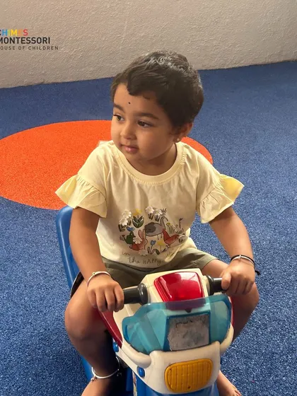 Welcome to Chimes. A new student enjoys a ride in our indoor play area, a space designed for safe exploration and fun, even for our youngest toddlers.