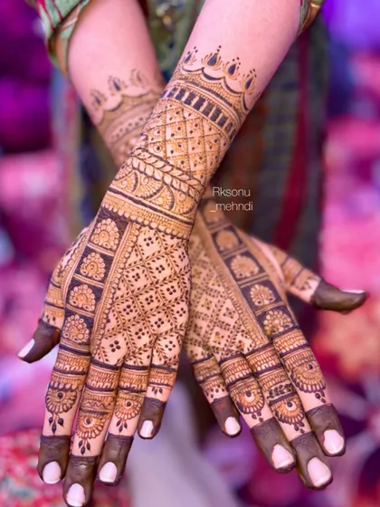 A very neat and intricate full-hand design featuring dense geometric jaali work. The pattern extends up the arm with clean, symmetrical bands, perfect for the bride who loves precision.