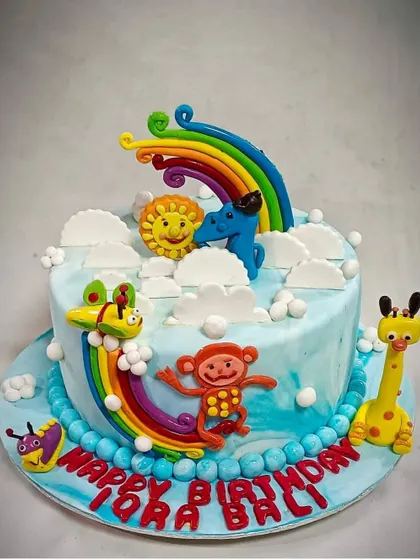 A birthday isn't complete without a cake. We can arrange for custom-themed cakes like this adorable one, featuring a rainbow, clouds, and cute animal characters, perfect for a child's party.