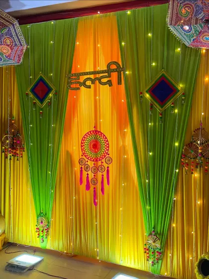 A traditional Haldi ceremony backdrop. The setup uses bright yellow and lime green drapes, accented with fairy lights, dreamcatchers, and colorful Rajasthani hangings.