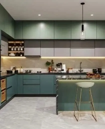 A beautiful kitchen with muted green and grey cabinets and a small breakfast island. The gold-accented bar stools and pendant lights add a touch of modern elegance.