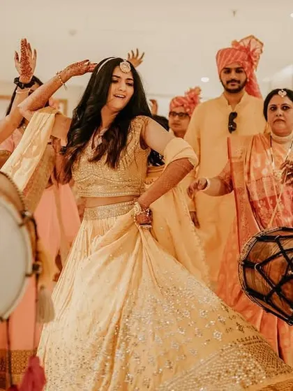 The bride's grand entrance to the Sangeet, dancing her heart out amidst dhol players and cheering guests.