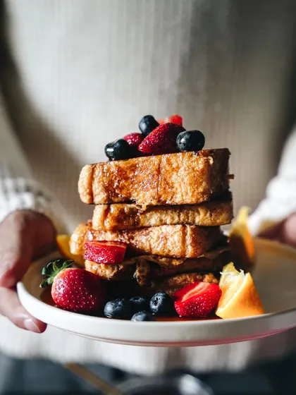 A stack of French toast held up for the camera. This shot feels personal and inviting, like someone is offering you a plate of delicious holiday breakfast.