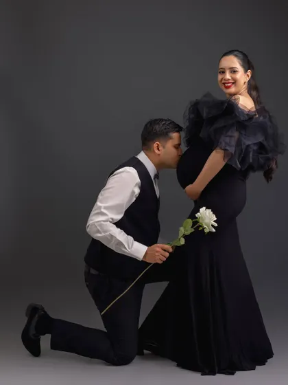 A classic and chivalrous pose with the father-to-be kneeling to kiss the baby bump, showing love and reverence for both mom and baby.
