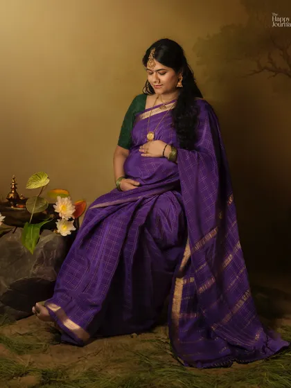 Seated amidst flowers and traditional elements, this expectant mother in a purple saree looks serene. My goal is to create a peaceful and beautiful setting for your traditional maternity portraits.