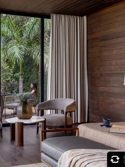 This bedroom offers a tranquil retreat with floor-to-ceiling windows that open onto a private deck. The wood-paneled walls and soft furnishings create a warm, cabin-like feel connected to the outdoors.