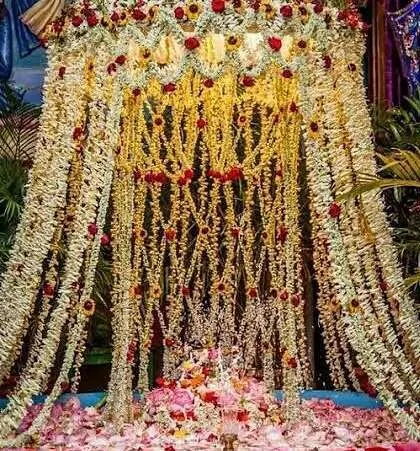 A 'Phoolon ki Holi' setup, perfect for Krishna bhakti events. A canopy made of jasmine and marigold strings creates a curtain of flowers, with a bed of rose petals below for a beautiful celebration.