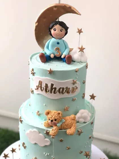A closer look at the top tier of the moon and teddy bear cake, showing the handcrafted boy and moon topper.