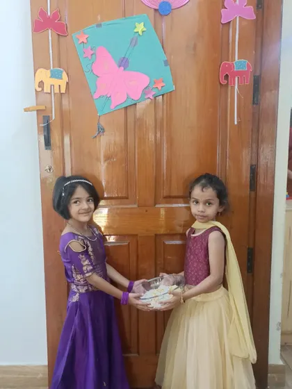 A duplicate of a previous image, showing two girls sharing 'Yellu Bella' for Makar Sankranti.