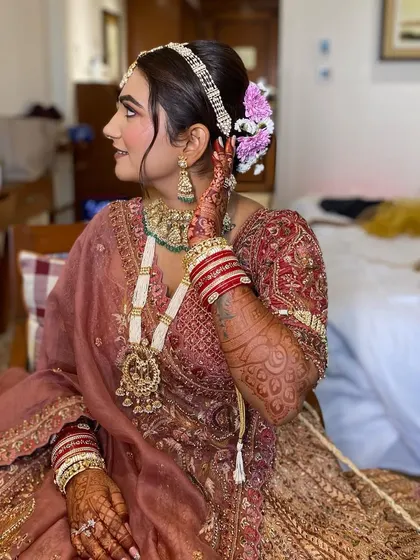 A side profile of Simran, showcasing her elegant floral bun and the soft contour of her makeup. Every angle is picture-perfect.