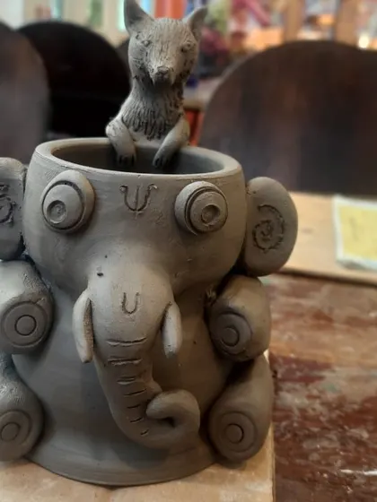 An intricate, unpainted elephant pot with a fox peeking out, ready for a creative painter to bring it to life with colour.