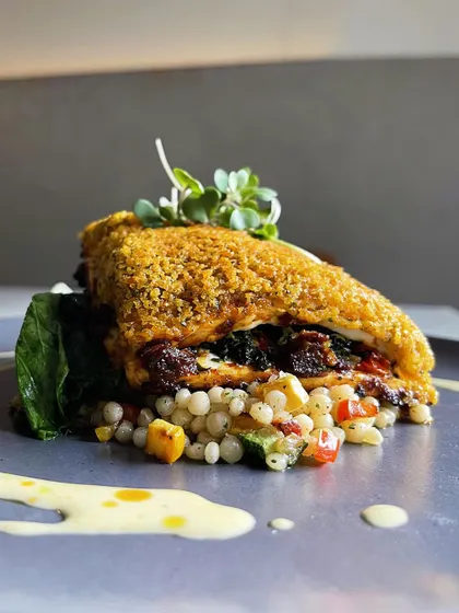 A side view of the cottage cheese steak, showing the layers of couscous, the thick steak, and the creamy jalapeño cheese fondue.