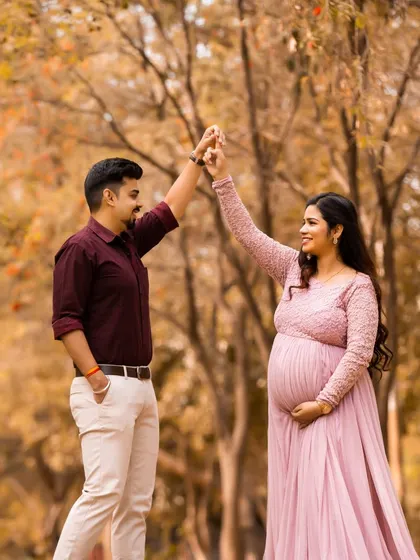 A playful dance in a park with beautiful autumn colors. This candid shot shows the fun and joy a couple shares as they await their new arrival.