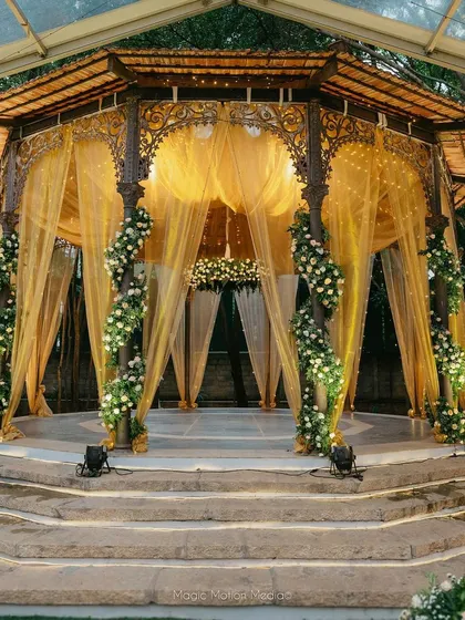 The reception stage, beautifully lit and draped in gold fabric with white floral accents. This classic and timeless design is perfect for a sophisticated evening celebration.