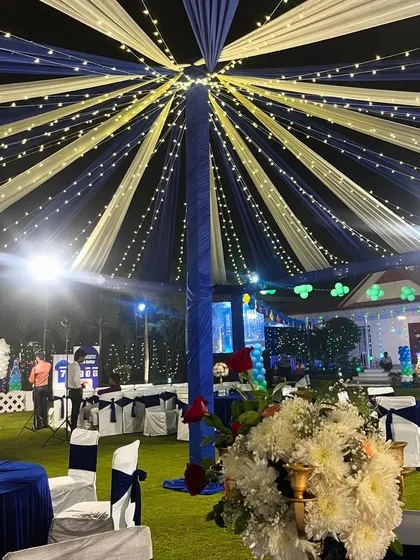 Another view of the magnificent blue and white tented decor for an outdoor Sangeet. The central pole supports the radial draping, with fairy lights twinkling between the fabric strips.