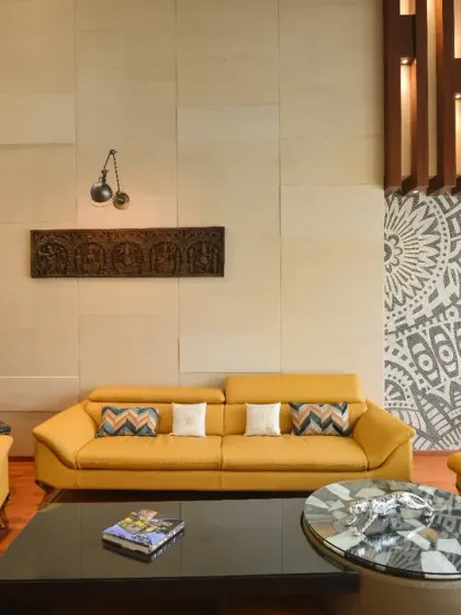 This double-height living room at Gupta Residence is defined by mustard-yellow seating and a bold patterned feature wall. The blend of art, light, and color creates a stylish yet welcoming ambiance.