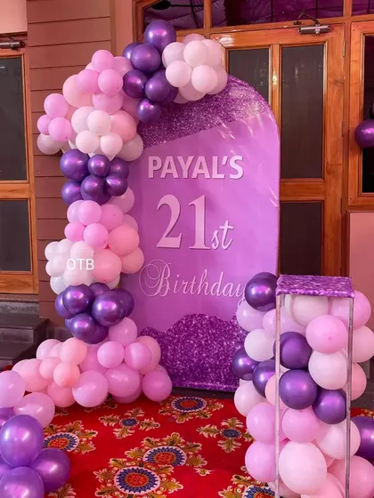 A glamorous 21st birthday setup in shades of purple and pink. The custom arch backdrop and balloon columns create a grand entrance feel.