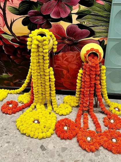 A creative twist on traditional decor. We used marigold flowers to create these unique floor arrangements flowing out of decorated pots.