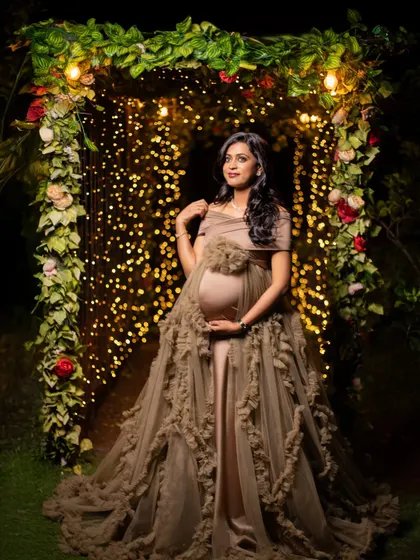 The full view of this gorgeous beige gown against a tunnel of lights. This is a truly magical setting for an evening maternity shoot.