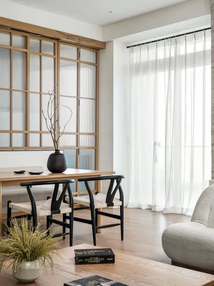 The dining area of the Urban Oasis project, featuring a white oak dining table and wishbone chairs. The sliding folding metal doors enhance the connection to the outdoor deck.