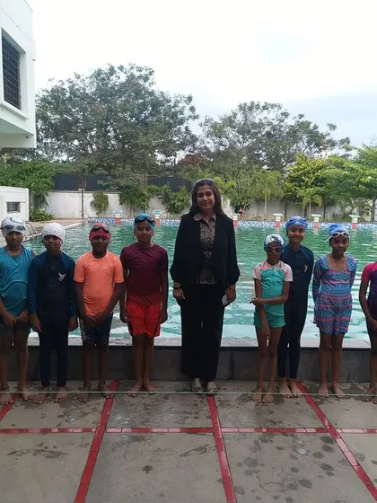 A team of swimmers stands proudly with their principal, celebrating their participation in the inter-house competition.