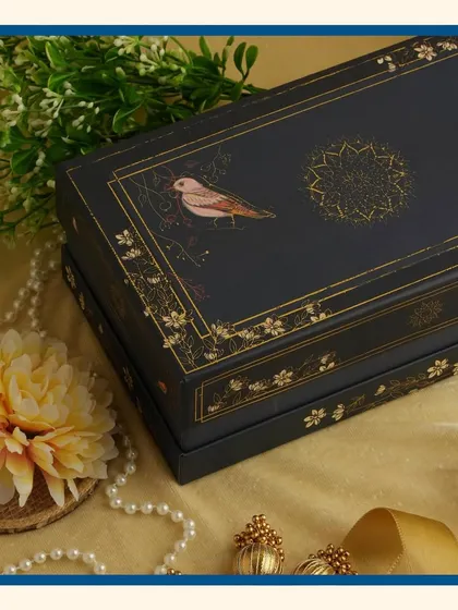 A close-up of the "Royal Blue" Diwali hamper box, highlighting the intricate gold foil detailing and bird illustrations.