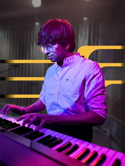 A keyboardist plays under the stage lights. We provide a full performance experience to make our students feel like the stars they are.