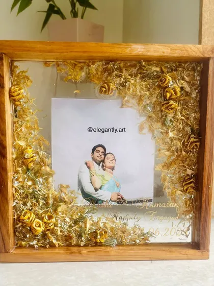 A beautiful teakwood frame preserving a wedding garland. The flowers are arranged in a floating style, creating a light and airy feel that is both modern and timeless.