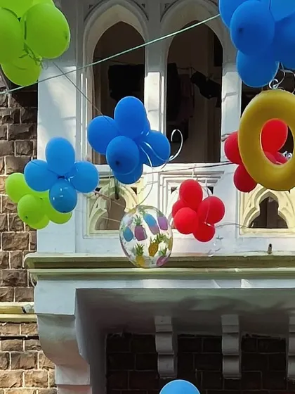 Colorful balloons, including some shaped like pool rings, hanging above the party area.