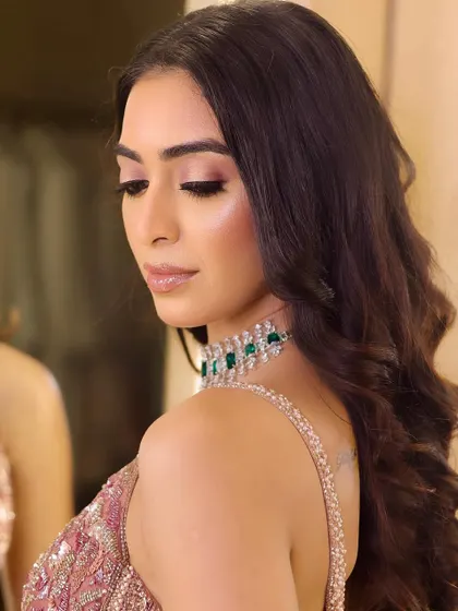 A beautiful over-the-shoulder pose that highlights the soft waves in the hair and the subtle shimmer on the eyelids, perfect for a cocktail evening.