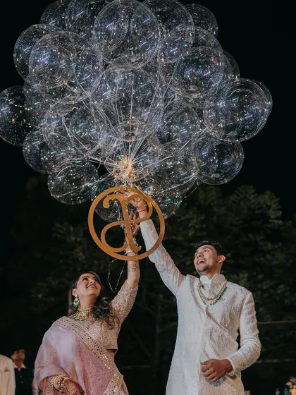 The couple releases a bouquet of illuminated balloons, a modern touch to a traditional celebration. The custom monogram adds a personal element to the moment.