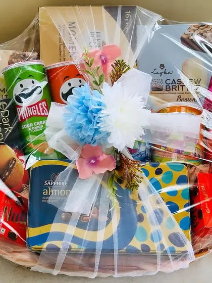 A fun and festive baby shower hamper, packed with a variety of snacks like Pringles and Dark Fantasy cookies, perfect for a celebration.
