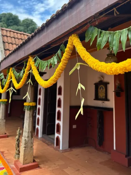 Simple marigold and mango leaf thorans (garlands) adorn the eaves of a traditional home, adding a touch of festive color.