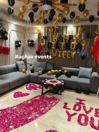 A full view of the romantic living room decoration. The setup includes a rose petal pathway, 'I LOVE YOU' written on the floor, and 'Happy Birthday Wifey' foil balloons.