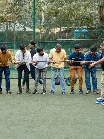A team works together, holding a long pole in a test of strength and coordination.