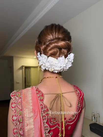 A beautiful braided bun adorned with a row of white flowers, a perfect look for a reception.