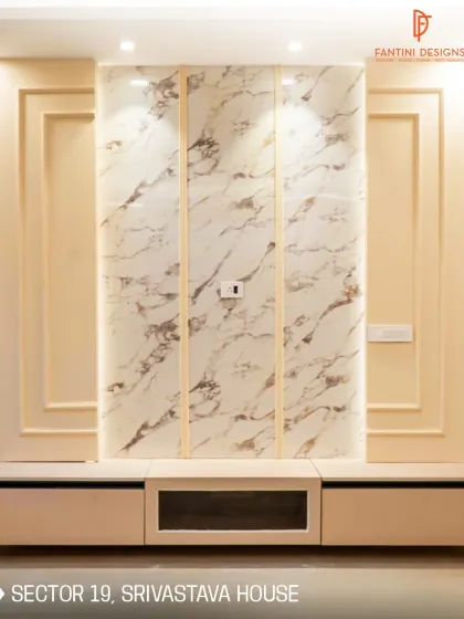 The TV unit in the Srivastava House features a beautiful book-matched marble panel framed by classic wall molding, creating a sophisticated focal point.