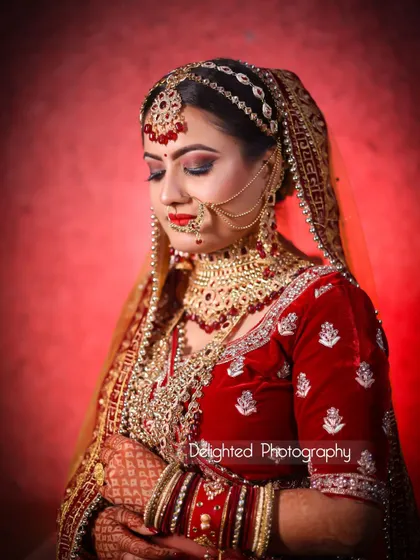 A beautiful full-length bridal portrait against a red backdrop. Her serene expression and stunning traditional attire are the centerpiece of this image.