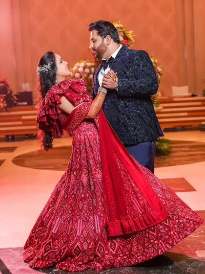 The couple shares their first dance, with the bride's vibrant red lehenga twirling beautifully. We capture the movement, joy, and romance of this classic reception moment.