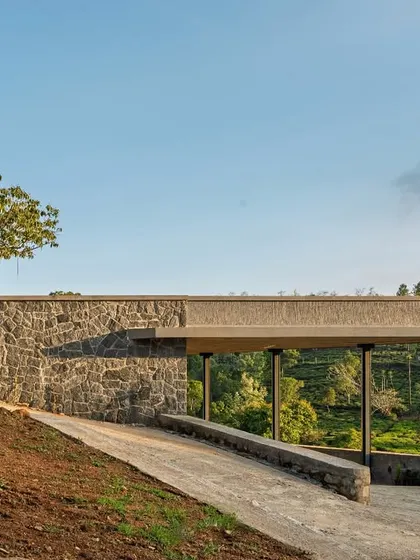 The carport of the Kotagiri retreat, nestled against a random rubble stone wall. This view shows how the structure is carefully placed to minimize disruption to the site and blend with the surrounding tea estates.