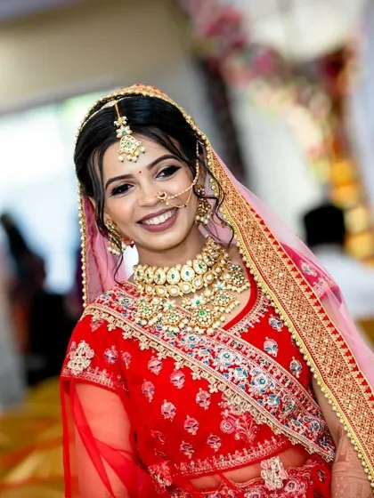 A beautiful bride smiling on her wedding day, wearing a full Kundan set with a choker, nath, and maang tikka. This is the classic look that never goes out of style.