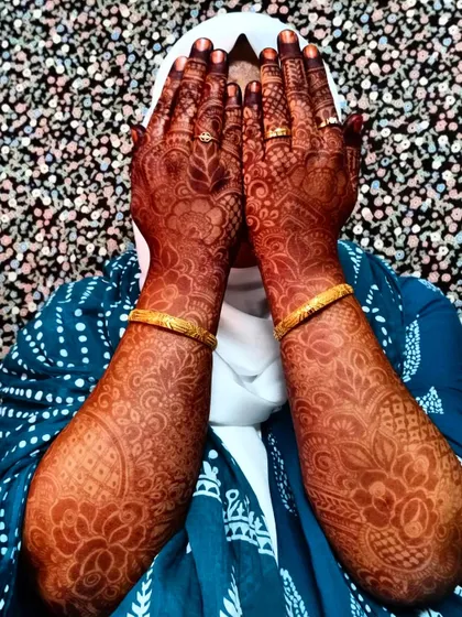A shy bride showing off her stunningly dark henna stain. The intricate patterns are beautifully defined by the rich color.