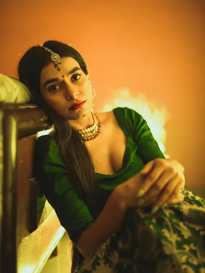 An indoor portrait with a vintage, moody aesthetic. The warm, directional lighting and the model's intense gaze create a cinematic and introspective character study, blurring the line between fashion and art.
