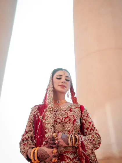 An artistic, low-angle shot of the bride, with the bright sky creating a powerful, angelic silhouette.