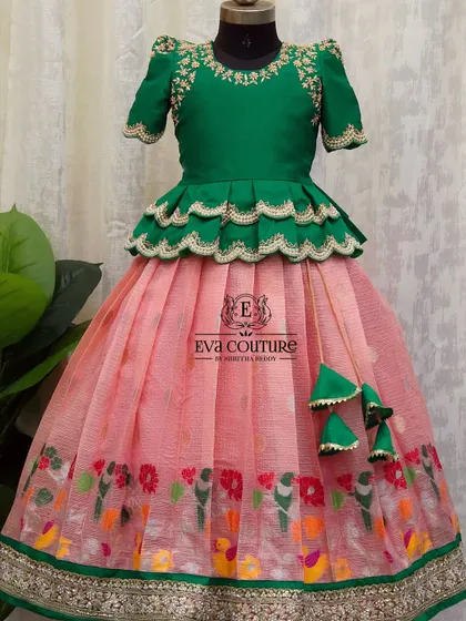 This lehenga features a pink organza skirt with a colorful bird and floral print border. The green peplum blouse has matching embroidery.