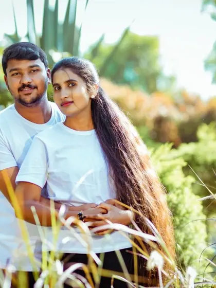 A couple in matching white tees poses for a portrait in a field. This is a classic, happy shot that captures their togetherness.