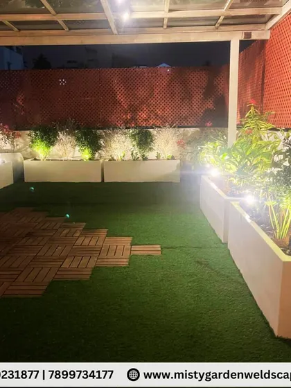 A beautiful night view of a terrace makeover in Banashankari. We used a glass pergola, artificial grass, and FRP planters with integrated lighting to create a peaceful and elegant family gathering space.