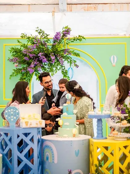 The cake-cutting moment, with the family gathered around the colorful and detailed hot air balloon-themed dessert table.