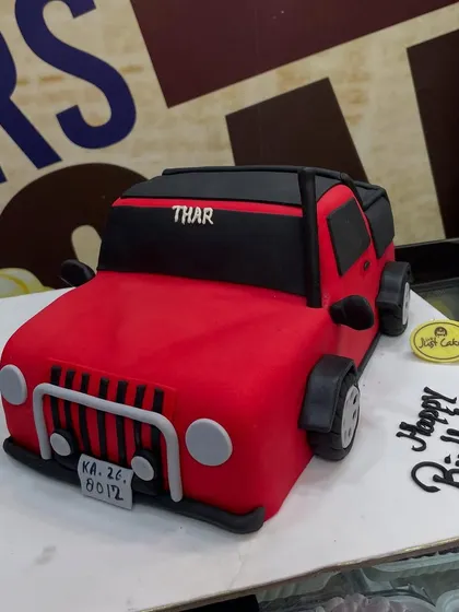 For the auto enthusiast, we crafted this 3kg cake meticulously sculpted into a vibrant red Thar jeep. Every detail, from the grille and wheels to the license plate, is handcrafted from fondant, demonstrating our skill in creating realistic 3D vehicle cakes.